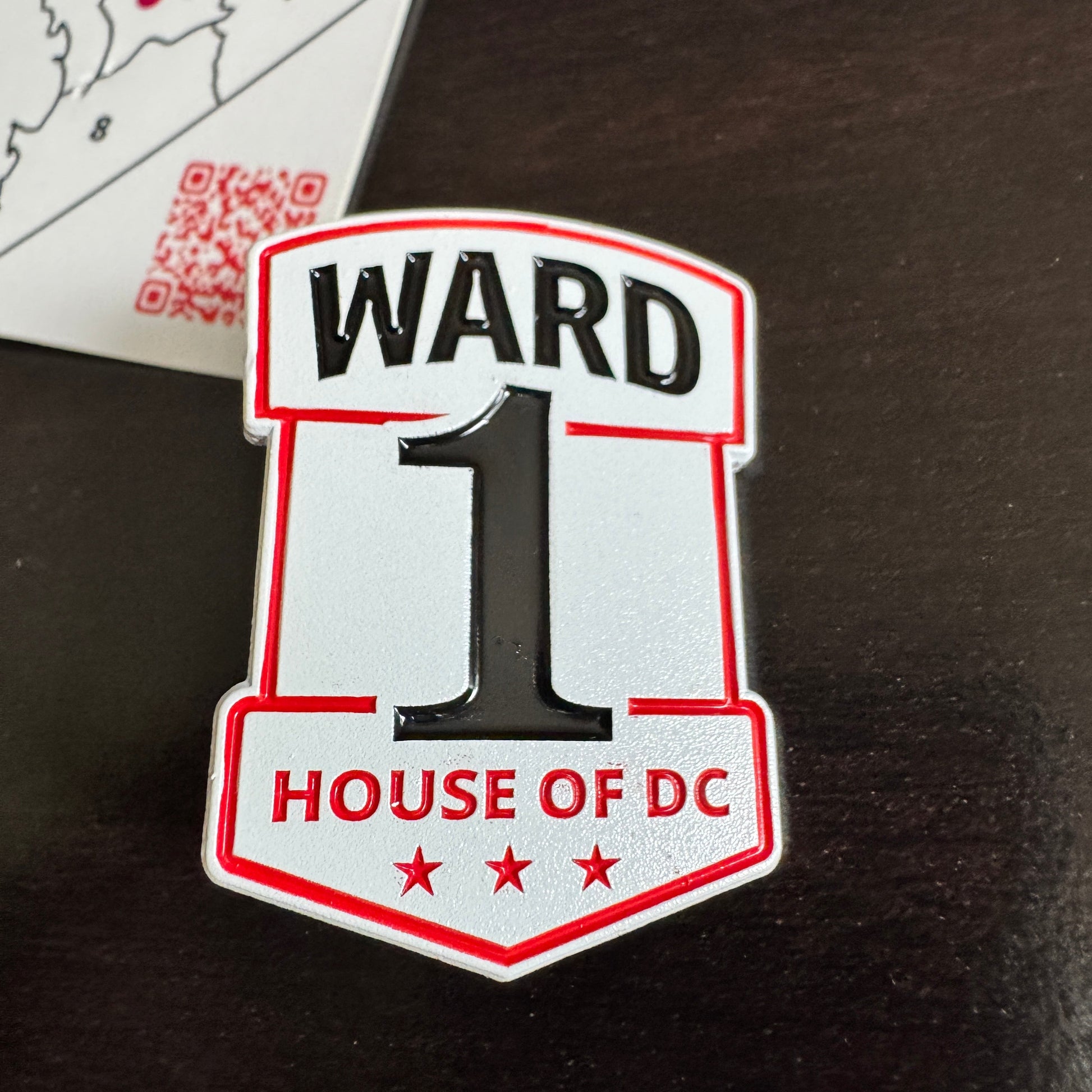 Ward 1 House of DC enamel pin — a white shield-shaped badge with red borders, black 'WARD 1' text, a large black number 1, 'HOUSE OF DC' in red, and three red stars."