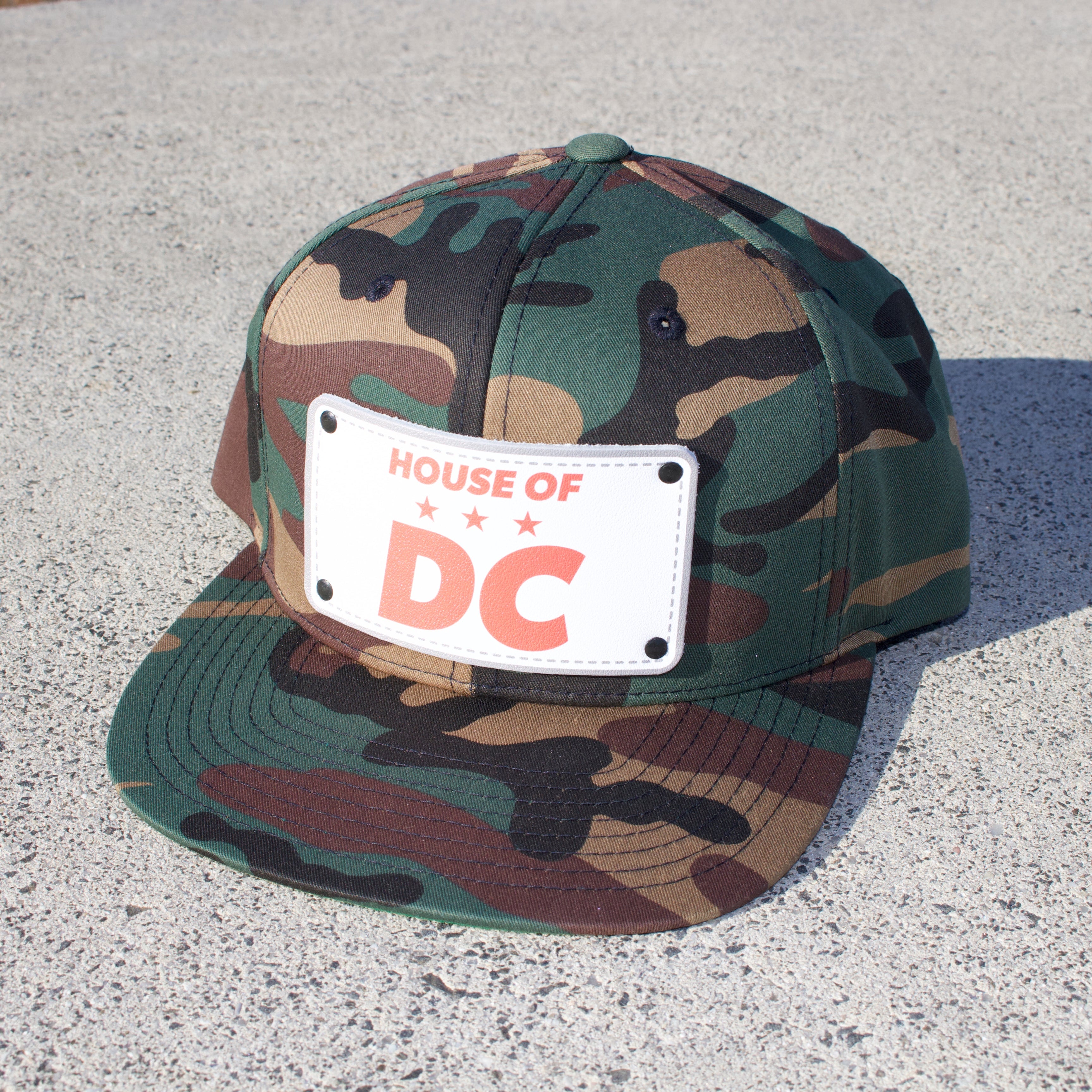 Camo hat that says HOUSE OF DC on concrete walkway.