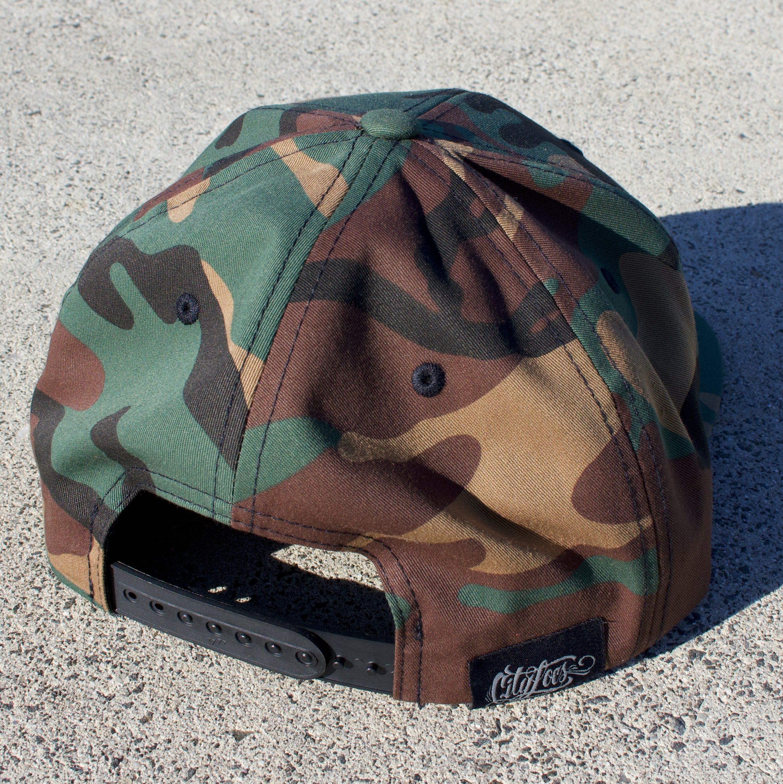 picture of camouflage ht with HOUSE OF DC logo back view of plastic snap adjuster